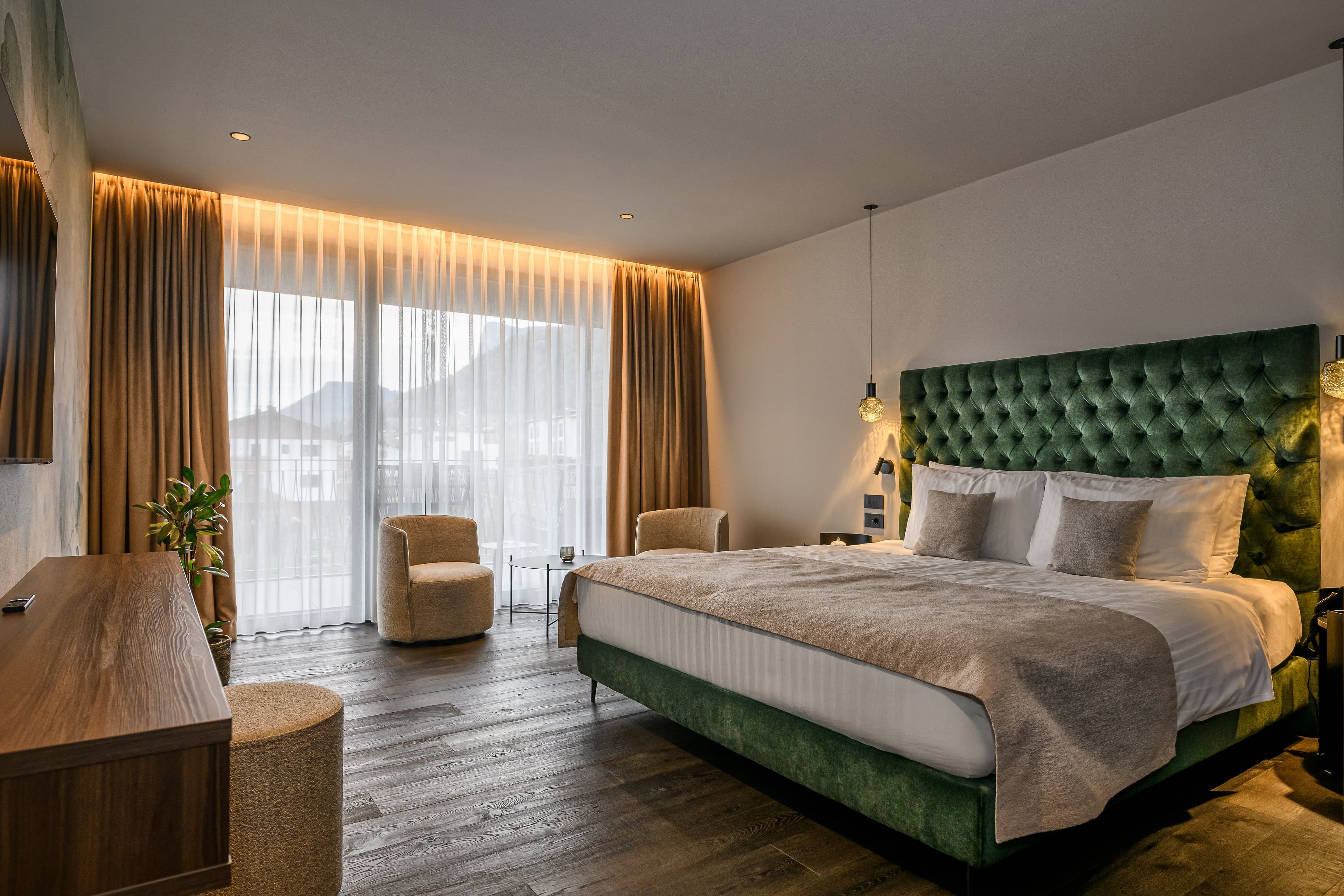 Bedroom with green tufted velvet headboard and balcony - Hotel Tirolensis