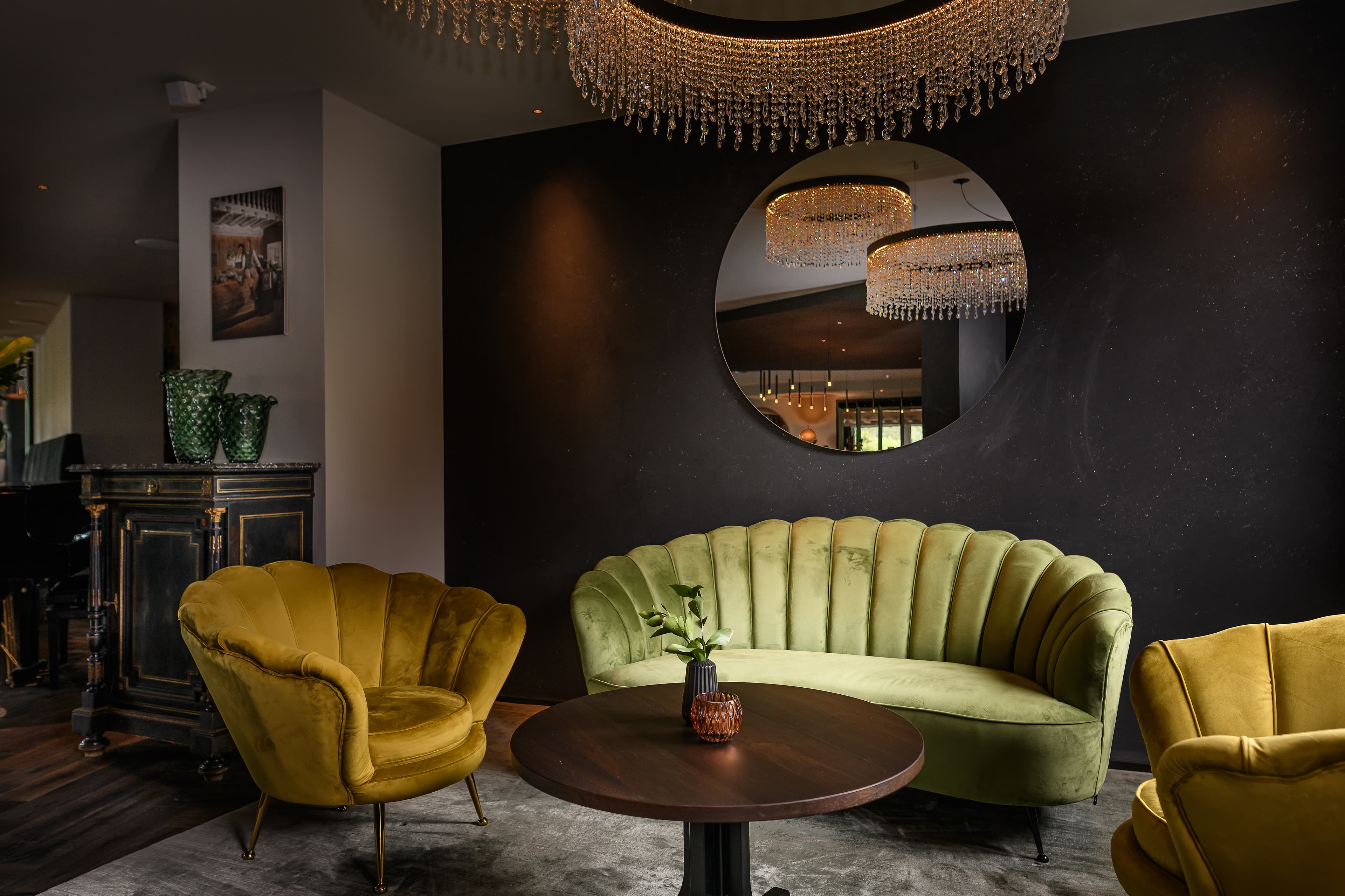 Lounge nook with green velvet sofa and crystal chandelier - Hotel Tirolensis